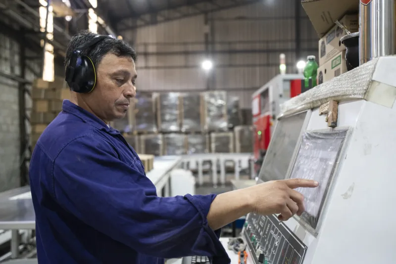 Operario de Rainap con protección auditiva operando el panel de una máquina