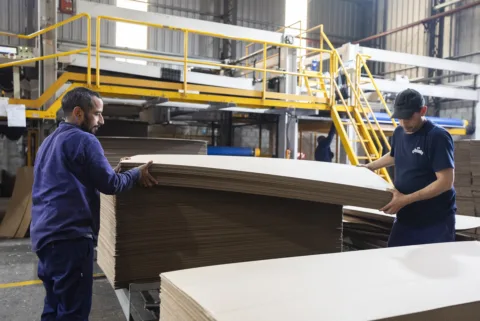 Operarios de Rainap acomodando planchas de cartón corrugado a la salida de la corrugadora
